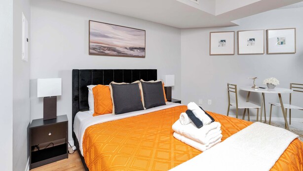 A hotel room with a bed, bedside tables, a desk, and chairs. - Bright Waterfront Studio Steps to DT Toronto (Toronto)