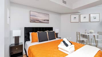Una habitación de hotel con cama, mesitas de noche, escritorio y sillas.