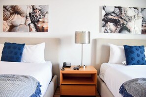 A hotel room with two beds, a nightstand with a lamp, and artwork on the walls. - Studio Pininfarina with Balcony & Stunning View (Hallandale Beach)