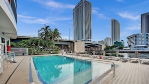 A rooftop pool with clear blue water, surrounded by palm trees and urban buildings. - Cozy Upper‑Level Studio with Fitness Center (Hallandale Beach)