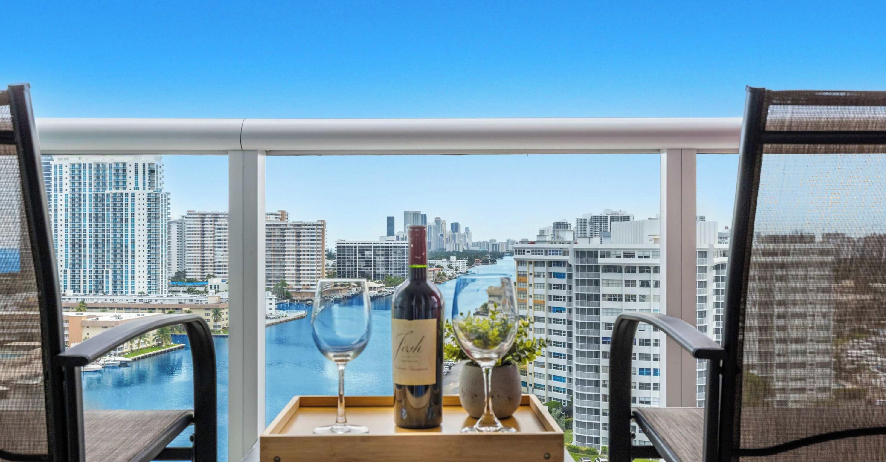 Ein Balkon mit Blick auf die Stadt, eine Weinflasche und ein Glas auf einem Tablett.