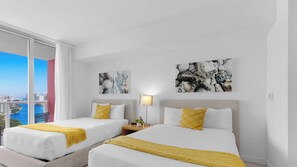 A hotel room with two beds, a large window with a city view, and artwork on the walls. - Stylish Studio Resort‑Style Bay View & Pool (Hallandale Beach)