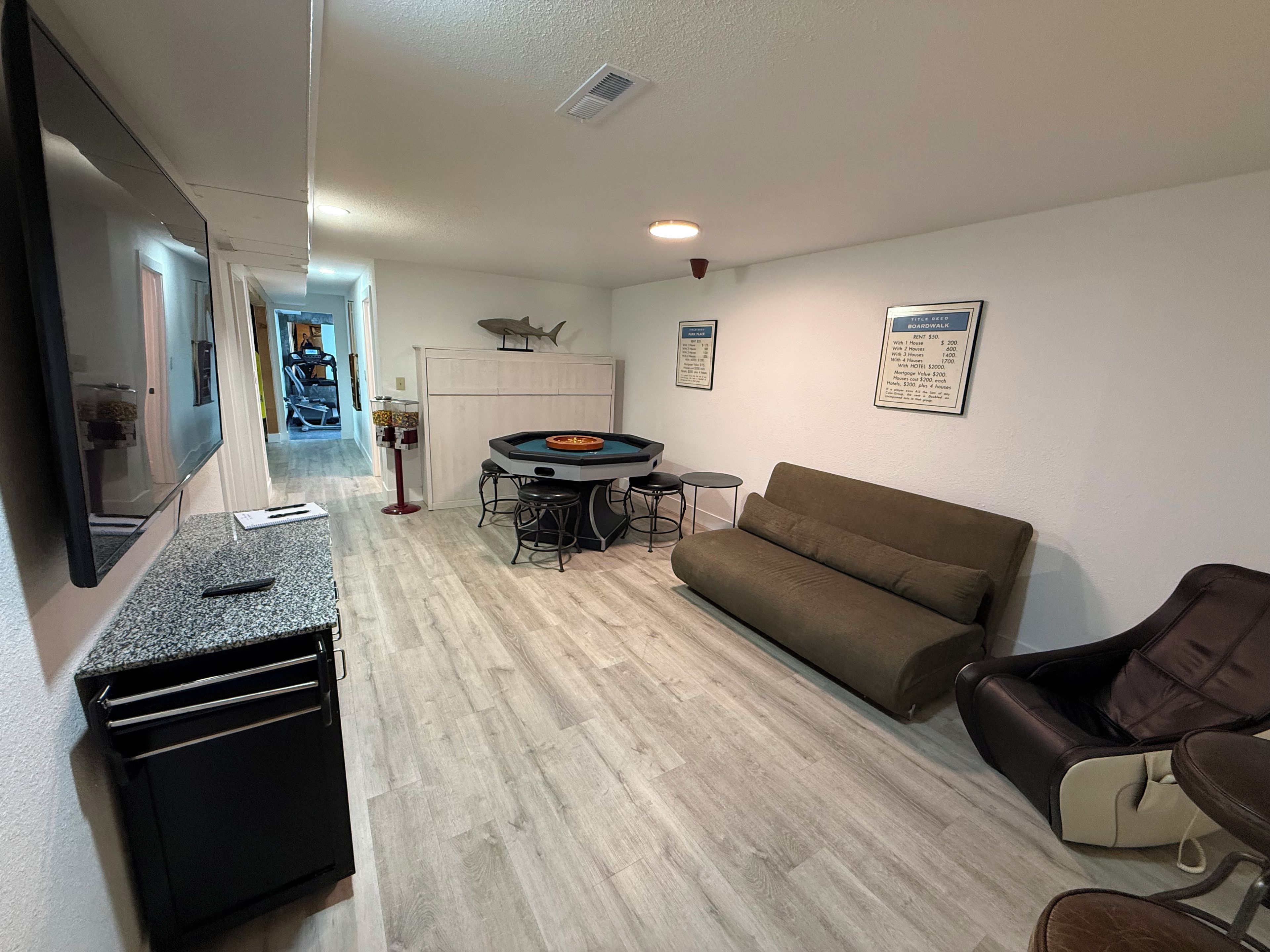 A living room with a sofa, a gaming table, and a TV.