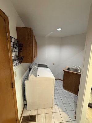 A compact laundry room with a washing machine, a drying rack, and a small sink.