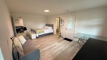 A bedroom with a bed, a desk, a chair, and a bicycle.