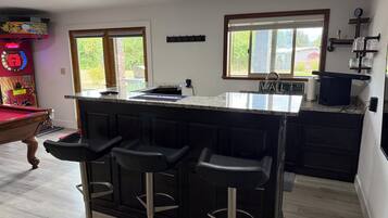 A kitchen with a bar area, a pool table, and a view of the outdoors.