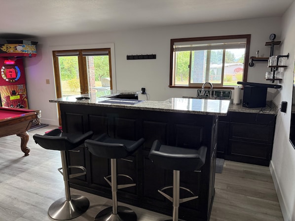 A kitchen with a bar area, a pool table, and a view of the outdoors.