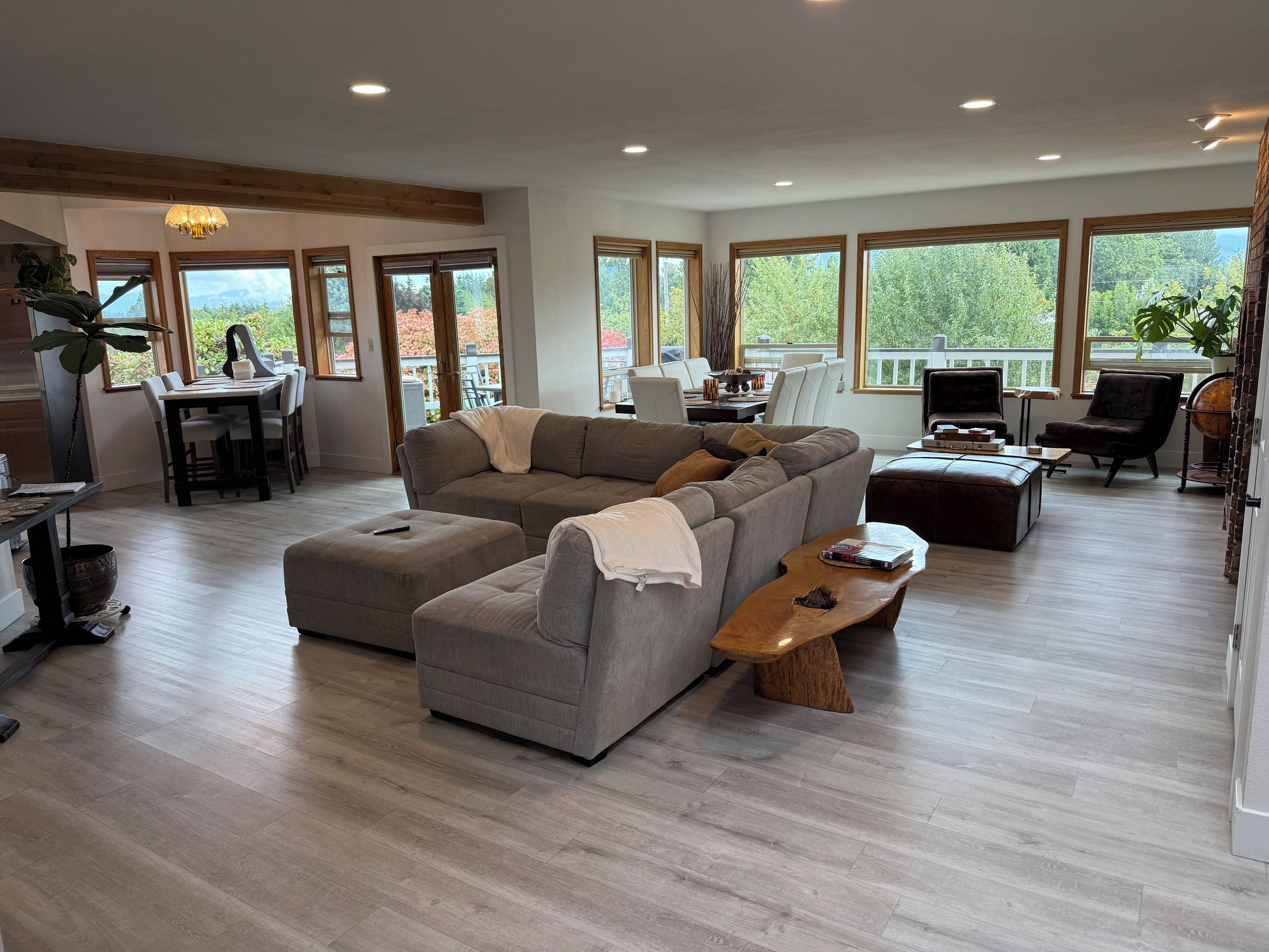 A spacious living room with a sectional sofa, a wooden coffee table, and a dining area with a table and chairs.