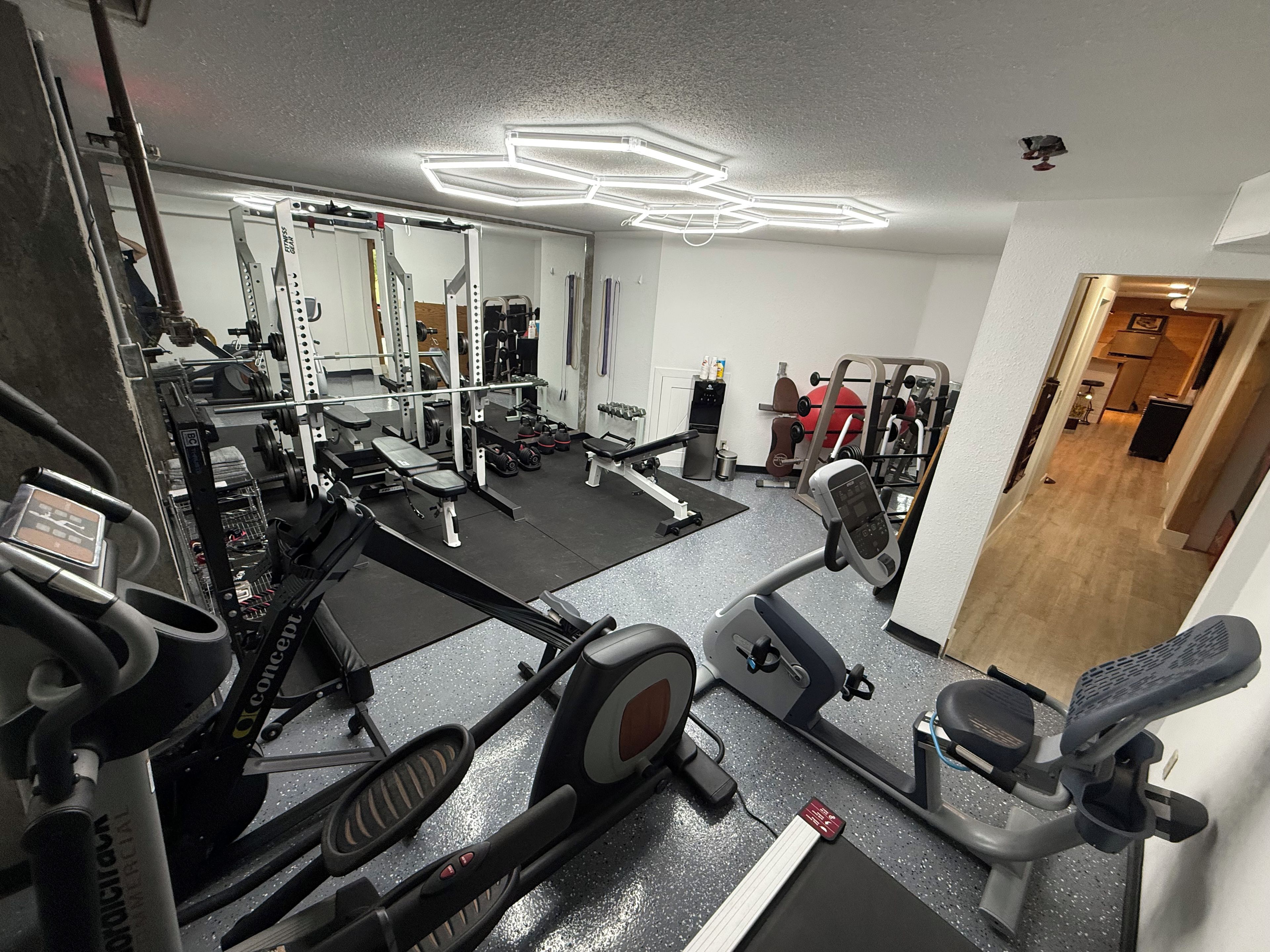 A home gym with various exercise equipment, including a treadmill, stationary bike, and weight machines.