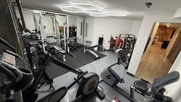 A home gym with various exercise equipment, including a treadmill, stationary bike, and weight machines.