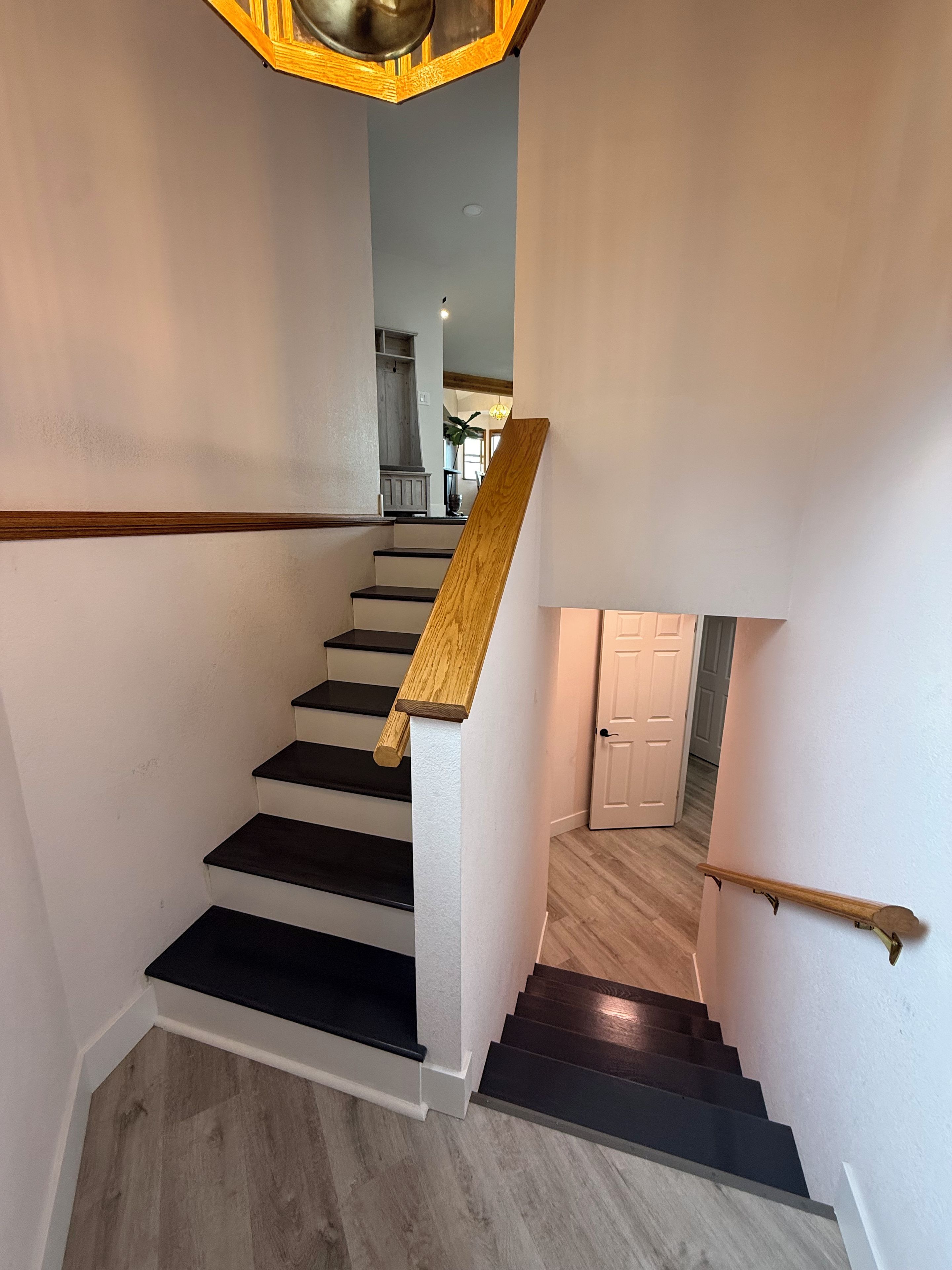 A staircase with wooden handrails and black steps leading to a door.