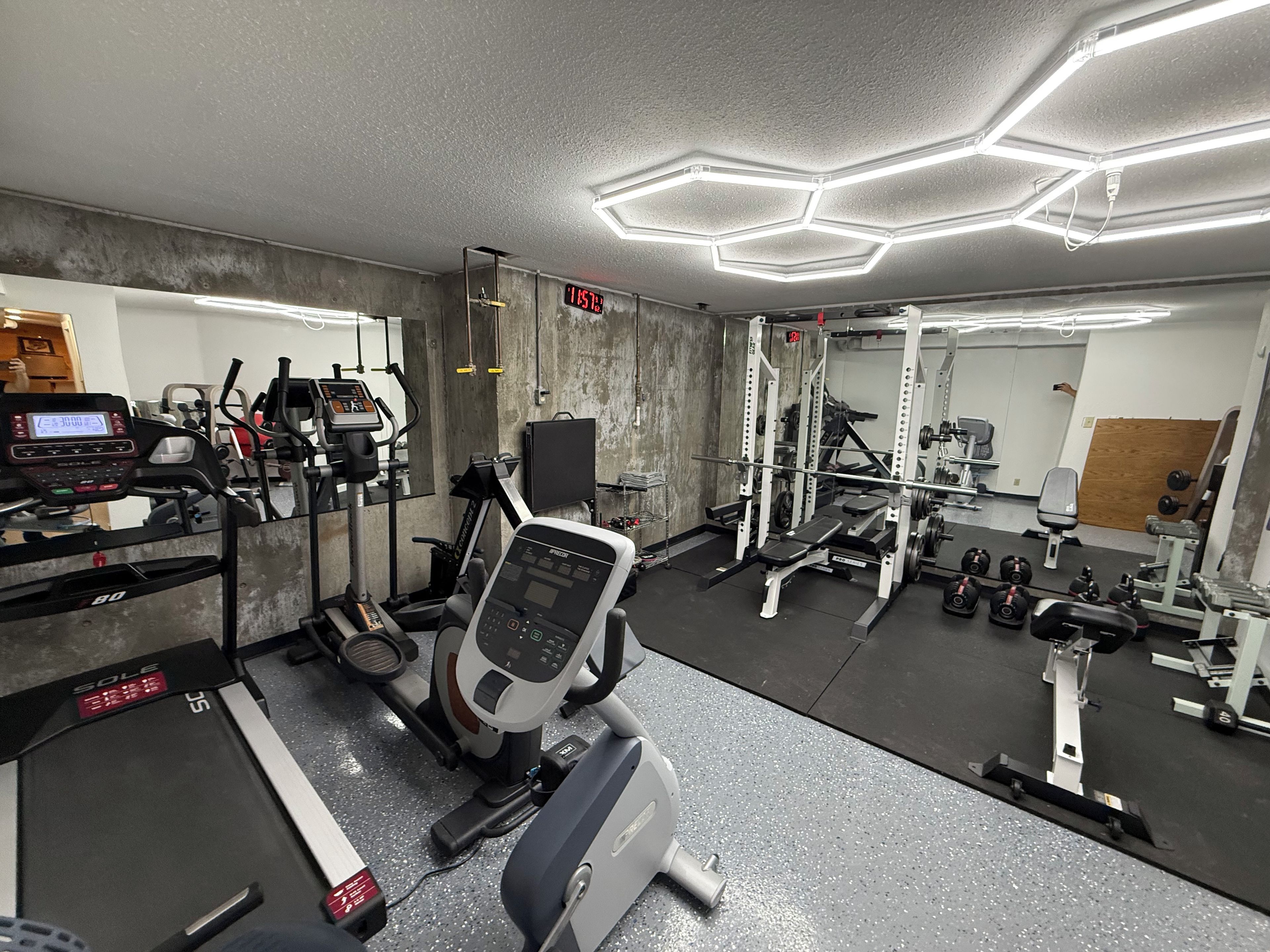 Un gimnasio con diversos equipos de ejercicio, como cintas de correr, una bicicleta estática y máquinas de pesas.