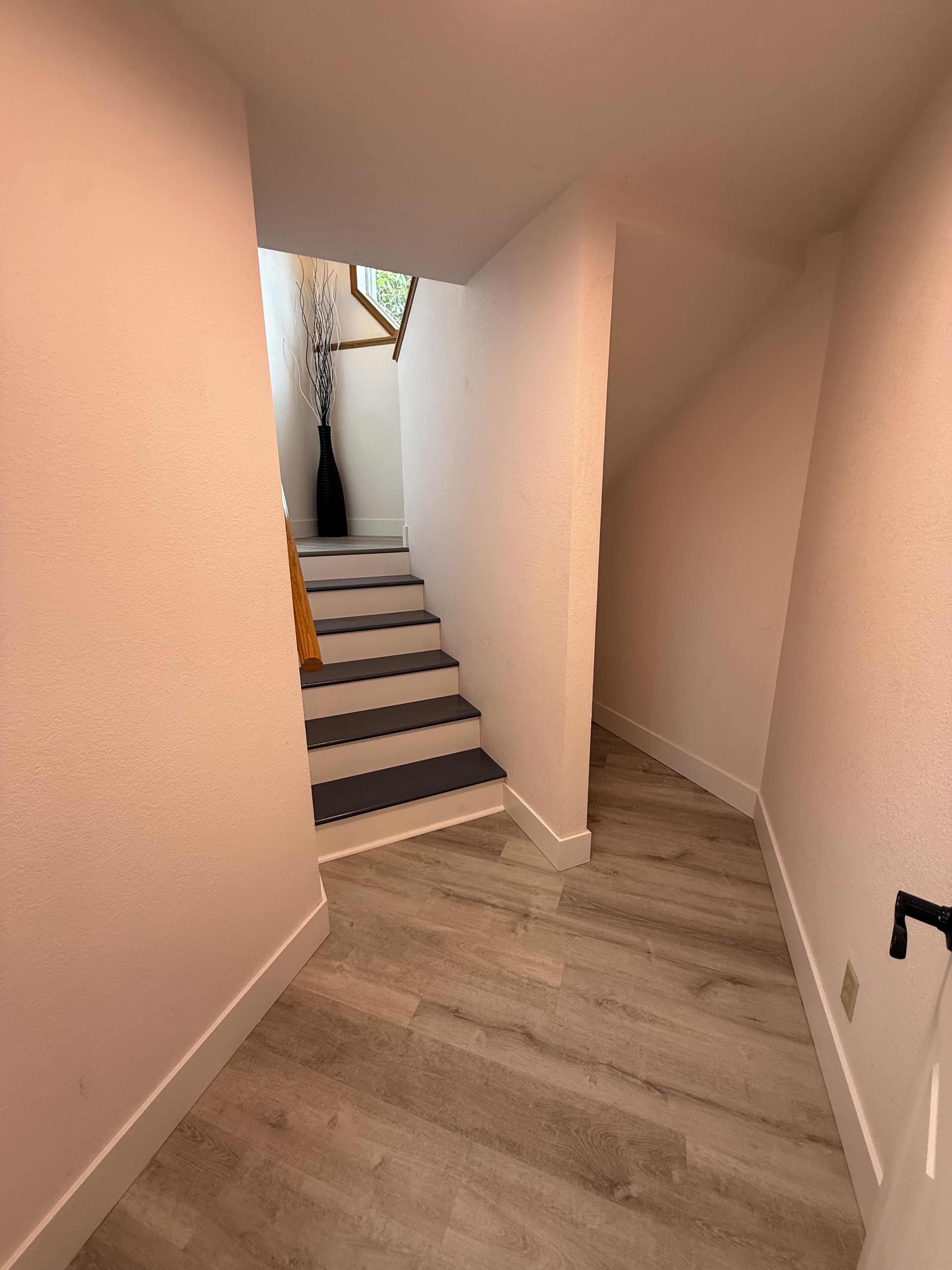 A staircase leading to a landing with a vase of branches on the landing.