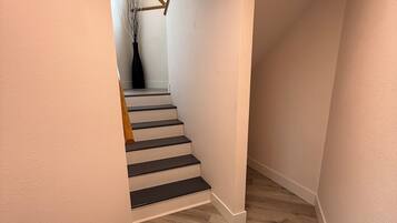 A staircase leading to a landing with a vase of branches on the landing.