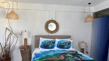 Un dormitorio con una cama, dos lámparas de pared, un espejo redondo y una planta en maceta.