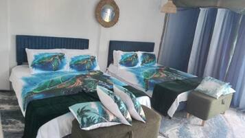 Un dormitorio con dos camas, una mesita, un espejo y una cortina.