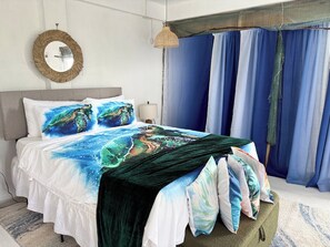 A bed with a sea turtle design, a round mirror, and blue curtains. - Turtle Nest Mayreau (Mayreau Island)