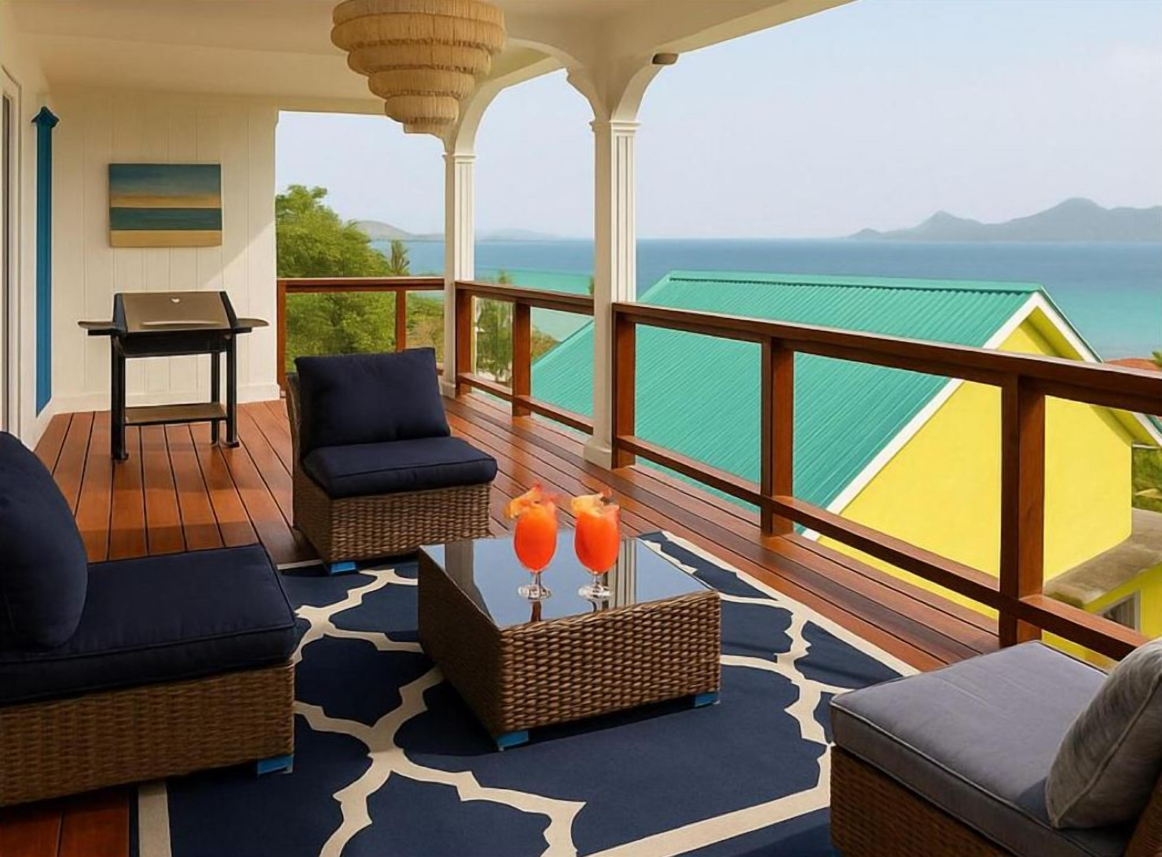 A balcony with wicker furniture, a table with drinks, and a view of the ocean.