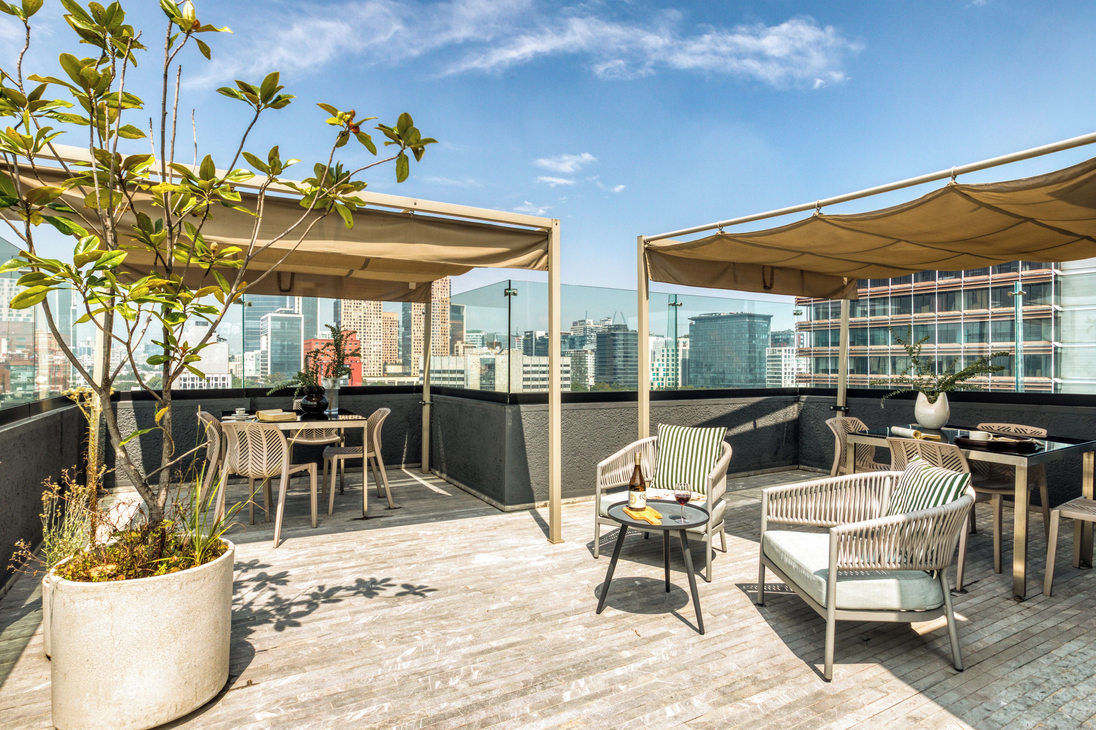 Une terrasse extérieure avec des sièges, une table et un pot de fleurs.