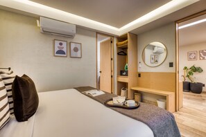 Una habitación de hotel con cama, mesita de noche y vestidor.