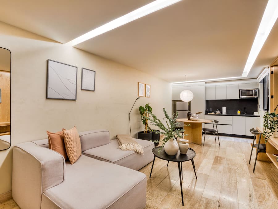 A modern living room with a sofa, a coffee table, and a kitchen in the background.