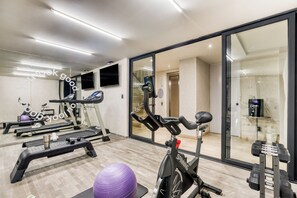 Une salle de sport équipée de matériel d’exercice, d’un tapis de course, d’un vélo d’appartement et d’un mur recouvert de miroirs.