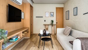 Una sala de estar moderna con una televisión de pantalla plana, un sofá, una mesa de centro y una estantería.