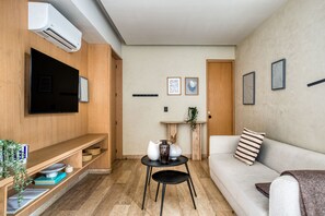 A modern living room with a flat-screen TV, a sofa, a coffee table, and a bookshelf. - ULIV Aristo Polanco (Ciudad de México)