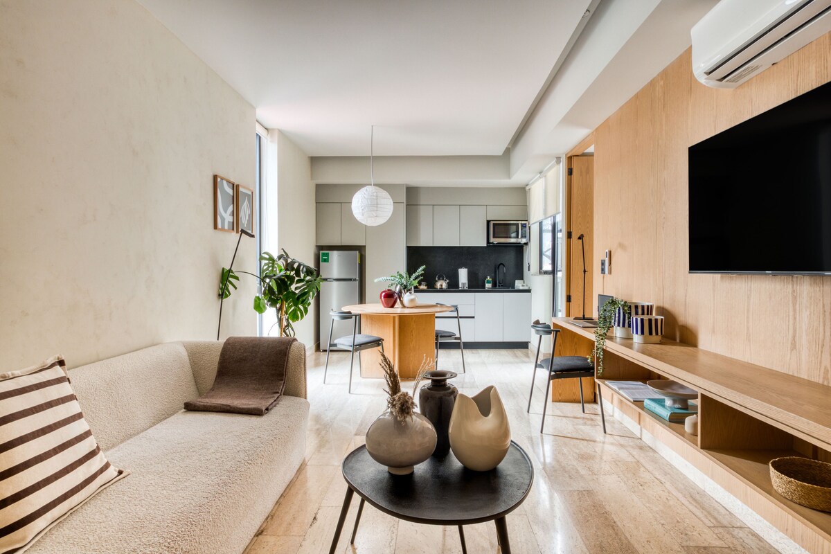 Una sala de estar moderna con un sofá, una mesa de comedor y una zona de cocina al fondo.