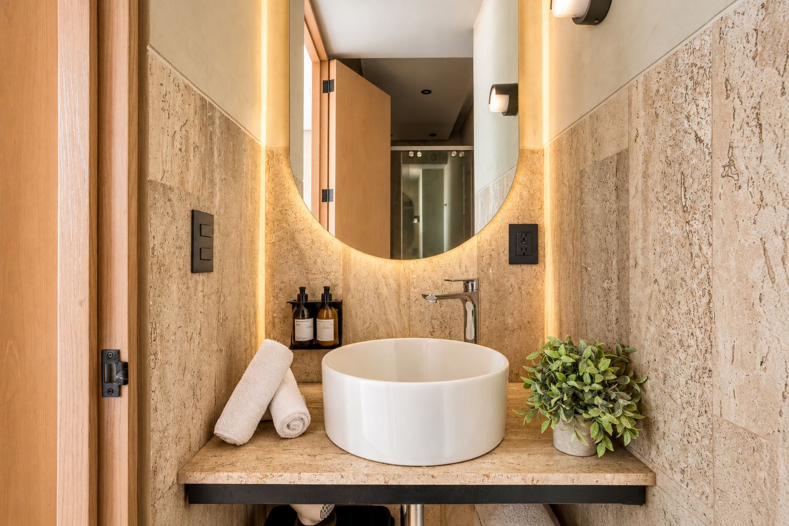 A modern bathroom with a freestanding bathtub, a mirror, a towel rack, and a small potted plant.