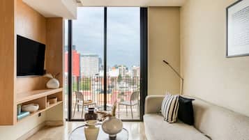 A modern living room with a large window, a flat-screen TV, a sofa, and a coffee table with decorative items.