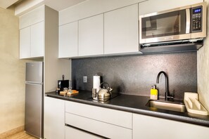 Una cocina moderna con microondas integrado, electrodomésticos de acero inoxidable y encimera negra.