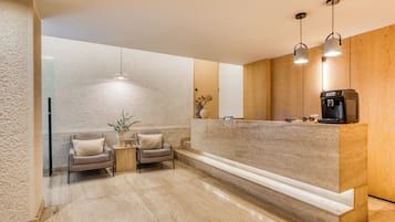 Cocina moderna con encimera de mármol, dos sillas, cafetera e iluminación colgante.