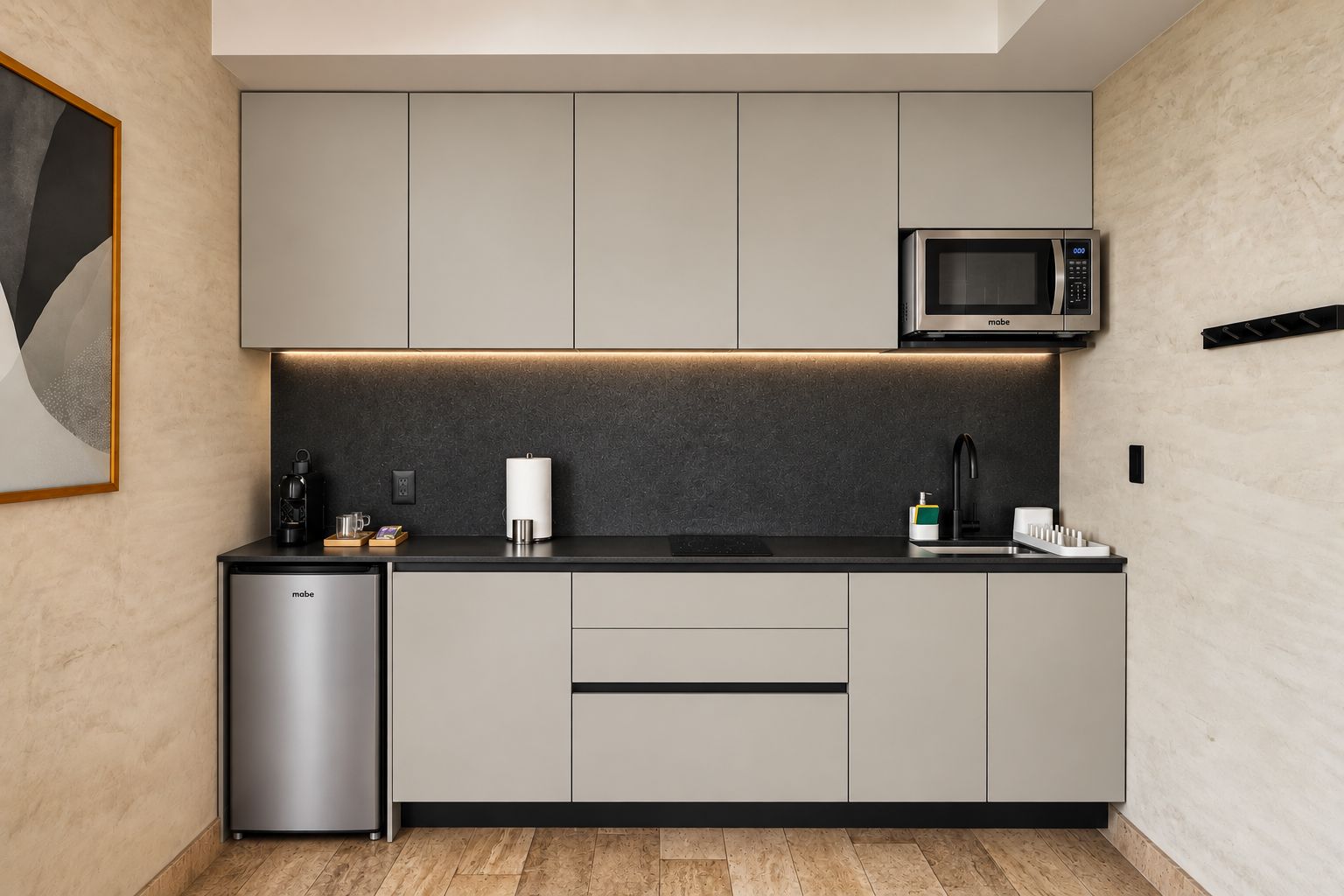 Una cocina moderna con gabinetes grises, un microondas integrado y un refrigerador pequeño.