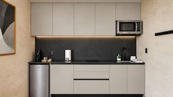 Una cocina moderna con gabinetes grises, un microondas integrado y un refrigerador pequeño.
