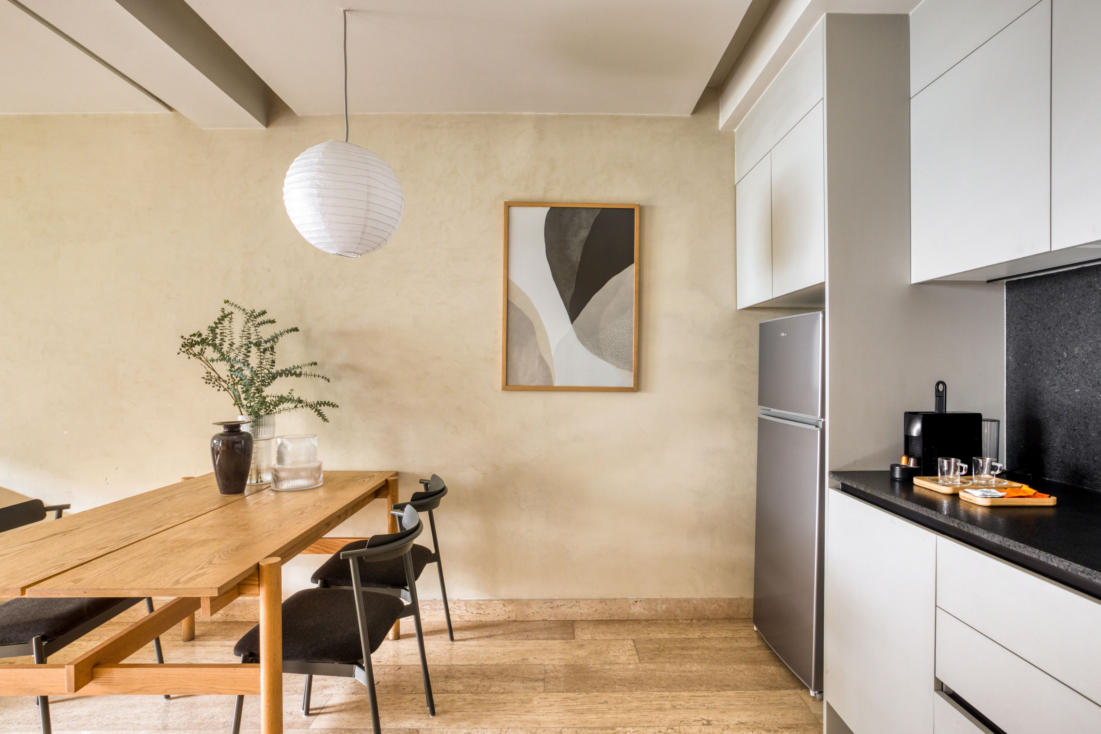 Eine moderne Küche mit einem eingebauten Kühlschrank, einem Holztisch mit Stühlen und einer hängenden Pendelleuchte.