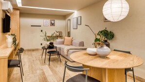 Una sala de estar moderna con una mesa de comedor redonda de madera, un sofá y un televisor montado en la pared.