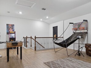 A spacious living area with a foosball table, a hammock chair, and a projector setup. - Spacious 5-bedroom house in awesome Seguin with EV charger and gym (Seguin)
