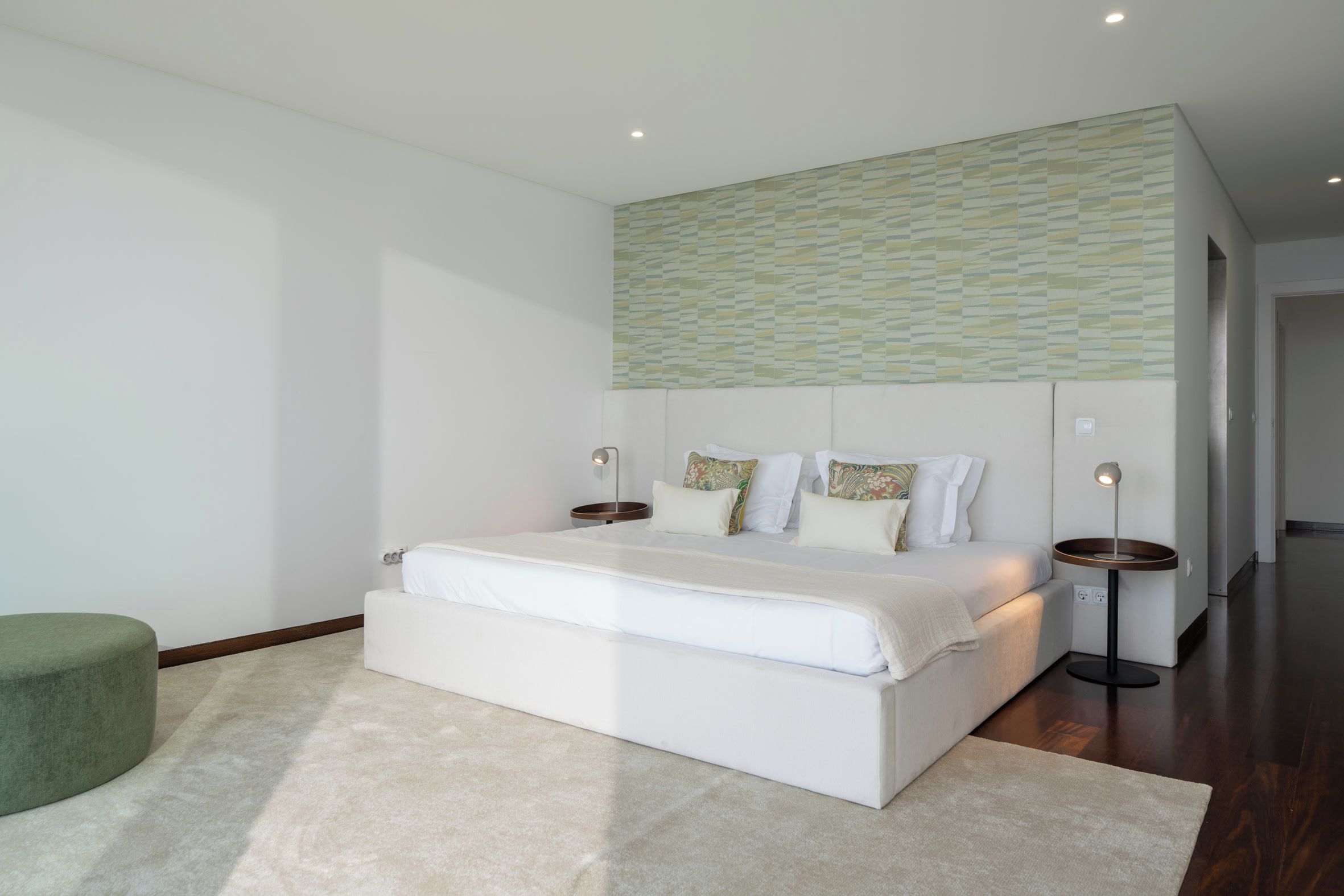 Une chambre moderne avec un grand lit, des lampes de chevet et un mur décoré d’un motif au-dessus du lit.
