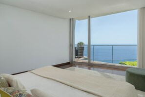 Une chambre dotée d’une grande porte-fenêtre coulissante donnant sur un balcon avec vue sur la mer.