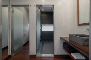 Une salle de bain moderne avec une porte d’entrée en verre, un lavabo intégré et un meuble-lavabo en bois.