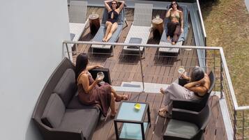 A deck with outdoor seating, including a sofa and chairs, and a small table.