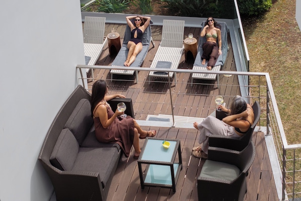 A deck with outdoor seating, including a sofa and chairs, and a small table.