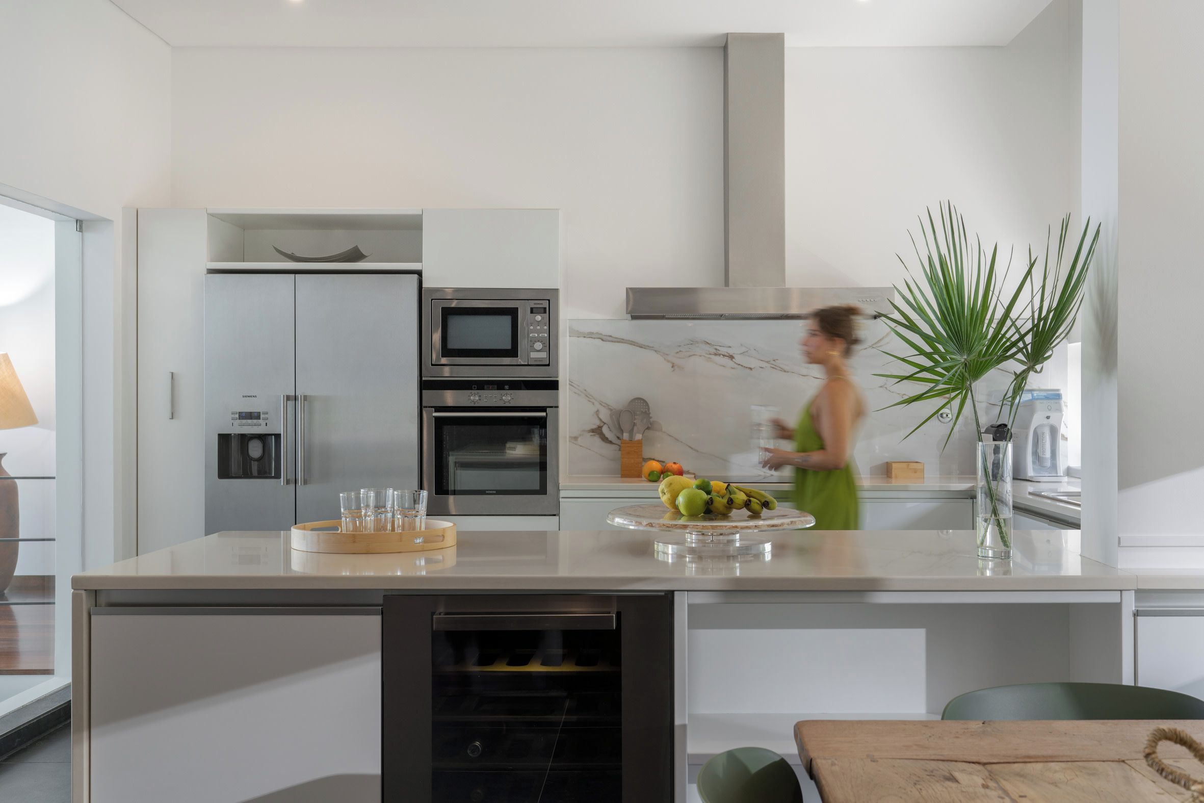 Uma cozinha moderna com forno embutido, micro-ondas e dispensador de água.