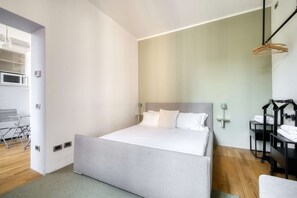 Ett modernt hotellrum med en säng, sängbord, ett skrivbord och en stol.