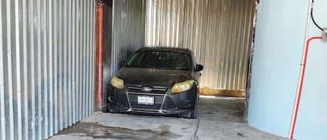 Un coche en un garaje con paredes de metal corrugado y suelo de hormigón.