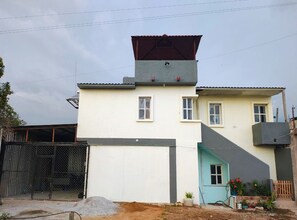 Ein zweistöckiges Gebäude mit Garage, einer kleinen Veranda und einem eingezäunten Bereich.