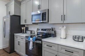 A modern kitchen with stainless steel appliances, including a refrigerator, microwave, toaster, and oven. - Cottage Grove Haven (Oxford)