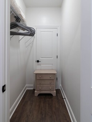 A narrow hallway with a white door, a small bench with drawers, and a coat rack with hanging items. - Cottage Grove Haven (Oxford)