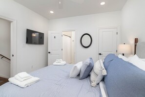 A bedroom with a bed, a TV, a mirror, and a door. - Cottage Grove Haven (Oxford)